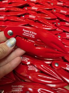 a person holding a red knife in front of a pile of red plastic knives with silver dots on them