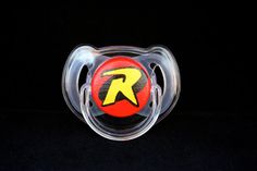 a pacifier with the letter r on it's side in front of a black background