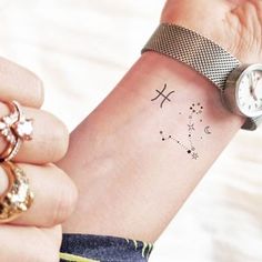 a woman's wrist tattoo with the zodiac sign and stars on her left arm