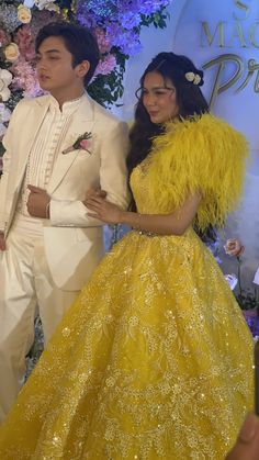 a man and woman in formal wear standing next to each other at a fashion show