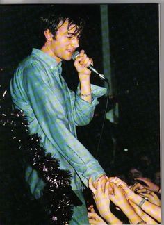 a man standing in front of a microphone with his hands on the hand of another person