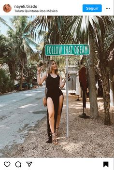 a woman standing under a street sign that says follow that dream on the side of the road