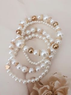 Upgrade your look with this stunning set of 4 faux pearl bracelets. Embrace timeless elegance with a mix of classic pearls and golden beads, perfect for adding a touch of sophistication to any outfit. These versatile bracelets are ideal for layering or wearing individually, suitable for both casual and formal occasions. Crafted with a sturdy and stretchy cord, they assure durability and style. Materials: faux pearls beads golden beads elastic cord White Stackable Pearl Bracelet, Stackable White Pearl Bracelet, Elegant Stackable Pearl Beaded Bracelets, White Pearl Stackable Bracelets, White Stackable Pearl Bracelet For Wedding, Elegant Stackable Round Bead Pearl Bracelet, Elegant Stackable Pearl Bracelet With Round Beads, Golden Bracelet, Pearls Bracelet