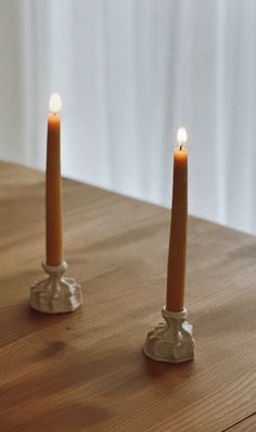 two candles sitting on top of a wooden table