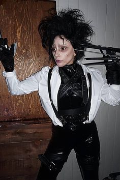 a woman dressed in black and white holding scissors