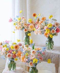 three vases filled with colorful flowers sitting on a table