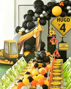 a construction themed birthday party with balloons and desserts on the table, along with an excavator truck