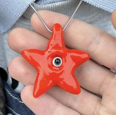 a person holding a red star shaped object with an evil eye in the center,