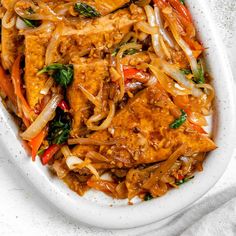 a white bowl filled with chicken and vegetables on top of a table next to a napkin