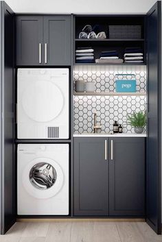 a washer and dryer in a small laundry room with gray cabinetry, white tile backsplash and shelves