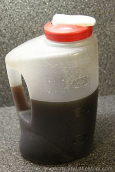 a gallon of liquid sitting on top of a counter next to a red and white cap