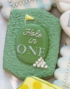 some cookies that have been decorated to look like they are holding golf balls and the words hole in one on them