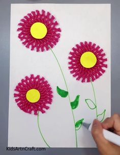 someone is drawing three flowers on paper