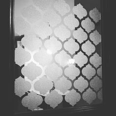 a window with an intricate pattern on the glass and light coming from behind it in black and white