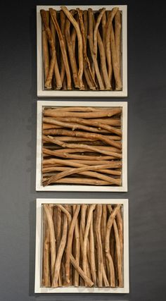 three pieces of art made out of branches on a gray wall with two white frames