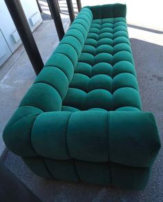 a green couch sitting on top of a cement floor