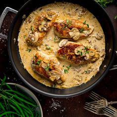 chicken with mushrooms and gravy in a skillet on a wooden table next to green beans