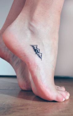 a woman's foot with a small triangle tattoo on the bottom of her ankle