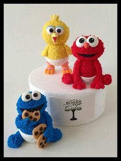 three crocheted sesame street characters sitting on top of a cake