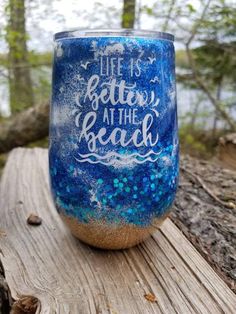 a blue and gold glittered wine glass with the words life is better at the beach on it