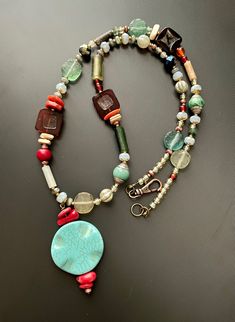 "Old and new come together in this stunning and eclectic holiday pendant necklace. Ancient Roman Glass beads nicely scattered with an eclectic mix of sparkle and color, including three modern red glass tile beads, all anchored with a light blue circular pendant.  This piece measures approx 25.5\" with two inch extension chain, finished with a decorative antique copper lobster claw clasp." Hippie Style Red Jewelry For Gift, Bohemian Czech Glass Pendant Beaded Necklace, Bohemian Glass Beaded Necklace With Natural Stones, Red Amulet Beaded Necklaces With Colorful Beads, Bohemian Czech Glass Necklace With Unique Variations, Red Amulet Necklace With Colorful Beads, Red Glass Jewelry For Festivals, One Of A Kind Bohemian Glass Jewelry, Red Glass Jewelry For Festival