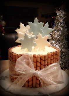 a cake decorated with icing and snowflakes on top of a table next to a christmas tree