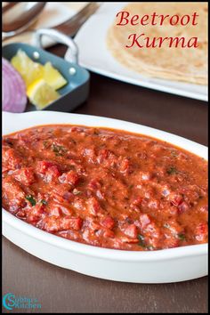 a bowl of beetroot kurma on a table next to a plate of pita bread