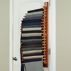 an open closet with clothes hanging on the door and folded up in front of it