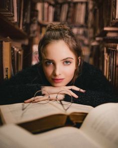 a woman laying on top of a bed next to a book shelf filled with books