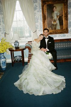 a bride and groom pose for a photo in front of a portrait on the wall