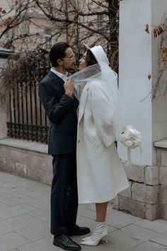 a man and woman standing next to each other in front of a building with trees