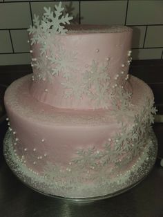 a three layer pink cake with white snowflakes on it