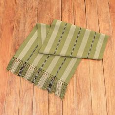 a green and white striped blanket laying on top of a wooden floor