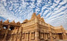 an elaborately carved building under a cloudy blue sky