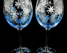 two wine glasses decorated with snowflakes and swirls are shown against a black background