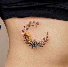 a woman's stomach with a sunflower and leaves tattoo on the side of her belly