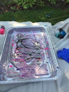 a plastic tray with melted paint on it sitting on a blanket next to some toys