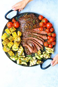 a plate with steak, grilled vegetables and corn on the cob is shown