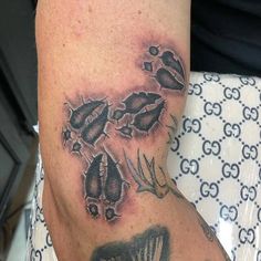 a close up of a person's arm with tattoos on it and an animal paw