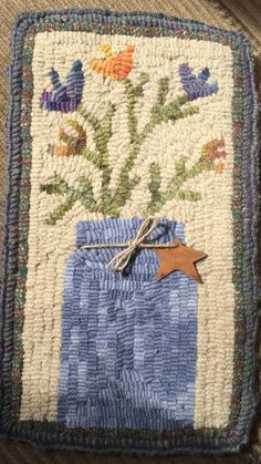 a blue vase with flowers is on the floor in front of a rug that has a brown star hanging from it