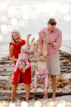 a man and two women are playing with a baby on the beach