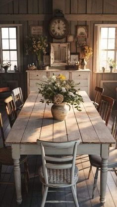 a wooden table sitting in the middle of a room with chairs and a clock on the wall