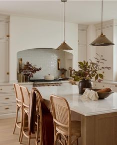 a kitchen with white cabinets and an island in the middle is surrounded by wooden chairs