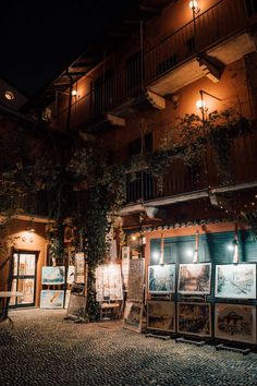 an outside view of a building at night with lights on and posters in the foreground