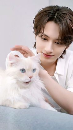 a woman petting a white cat with blue eyes