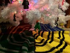 a white christmas tree is decorated with multicolored knitted ornaments and other holiday decorations