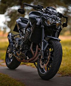 a black motorcycle parked on the side of a road next to a lush green field