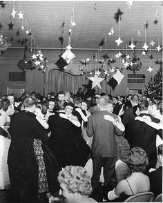 an old black and white photo of people dancing in a room with stars hanging from the ceiling