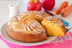 a bundt cake on a plate next to some carrots and an apple in the background