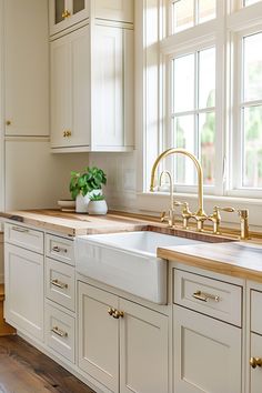 a kitchen with white cabinets and gold faucet, wood counter tops and wooden flooring